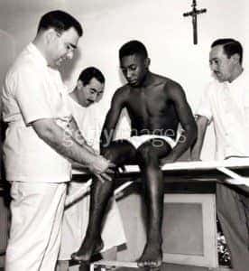 Pelé sobre uma mesa com pessoas de branco à volta