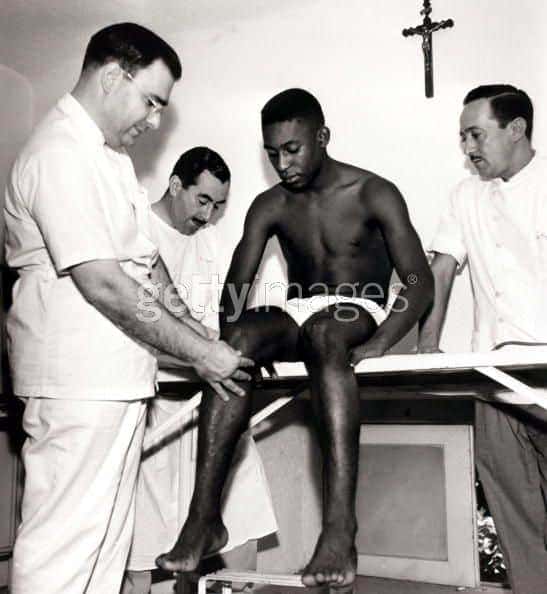 Pelé sobre uma mesa com pessoas de branco à volta