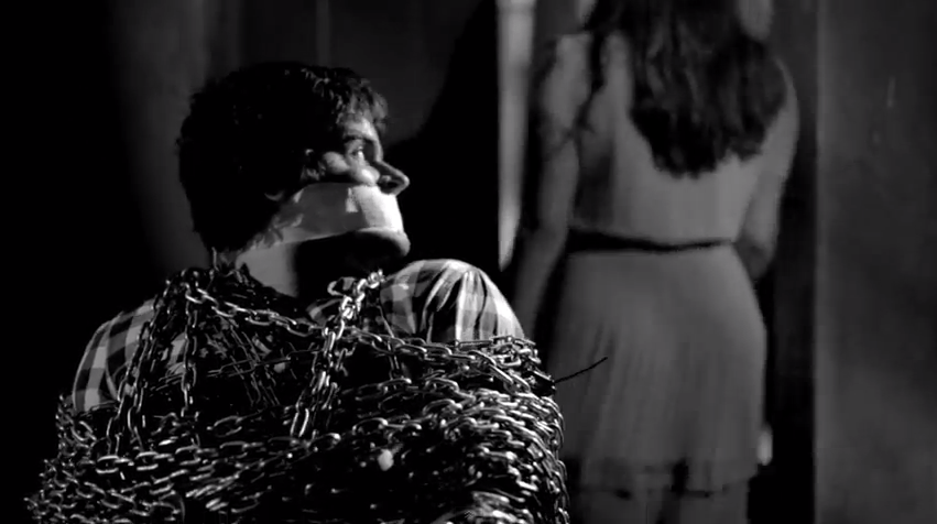 Homem acorrentado e mulher com faca. Clipe da música Clarice Falcão, Oitavo Andar