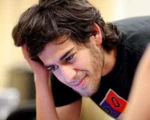 rapaz com cabelo pelo pescoço e barba por fazer, inclinado sobre mesa