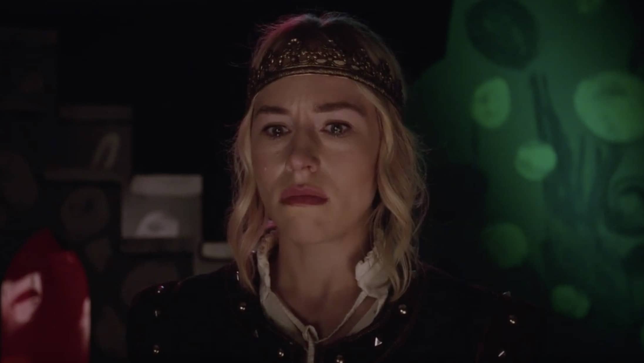 a blonde woman wearing medieval like clothes. We see her above midchest in a close up, almost frontaly, but she is facing some place behind us, to our left, but as seeing other place.
