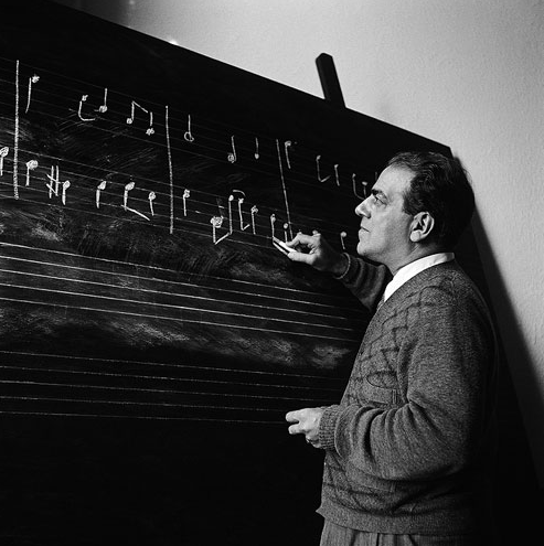 O Maestro Heitor Villa-Lobos desenhando notas musicais em lousa.