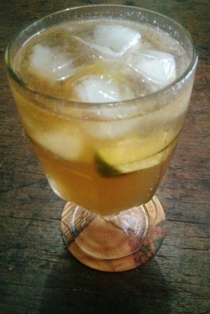traça de vidro com bebida com bastante gelo e limão, sobre mesa de madeira
